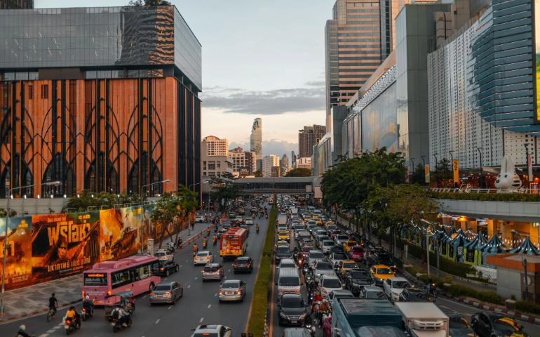 Vibrant cityscape of Bangkok at dusk with bustling traffic and skyline in view.