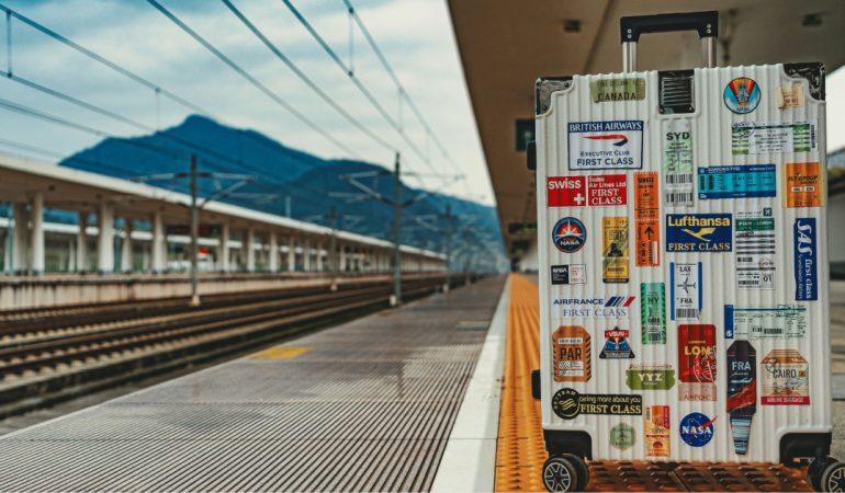 White suitcase adorned with travel stickers on empty railway platform,
ZhiCheng Zhang/Pexels