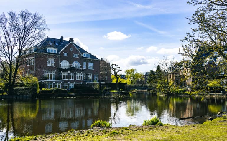 A large house sitting on the side of a river and lush trees