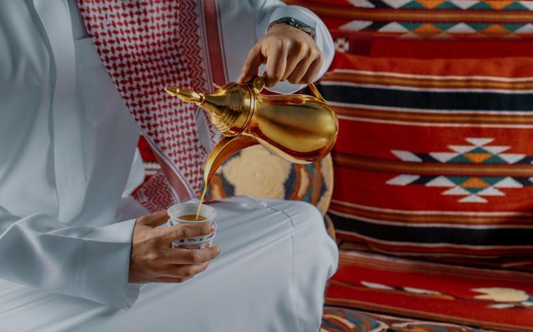 Arab Man serving traditional arabic coffee from a traditional pot