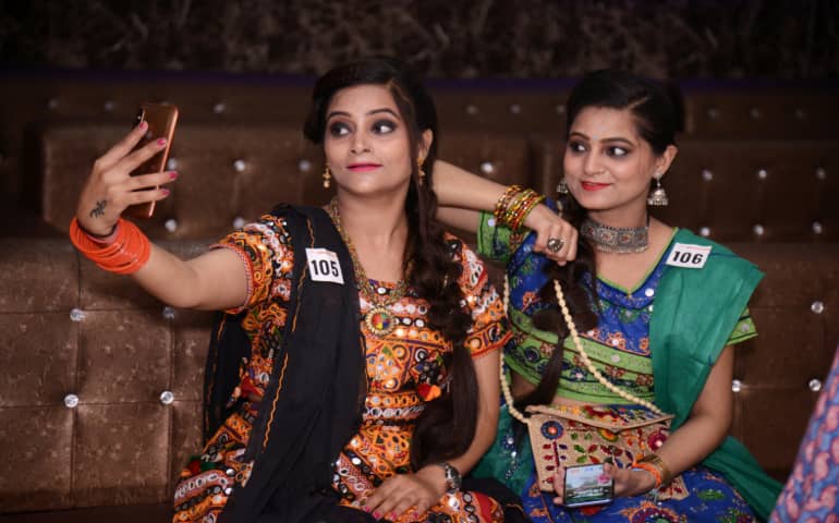 Women taking selfies on smartphone at Dandiya night on the occasion of Navaratri Dussehra
