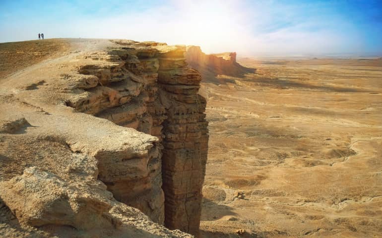 A man standing on top of the cliff