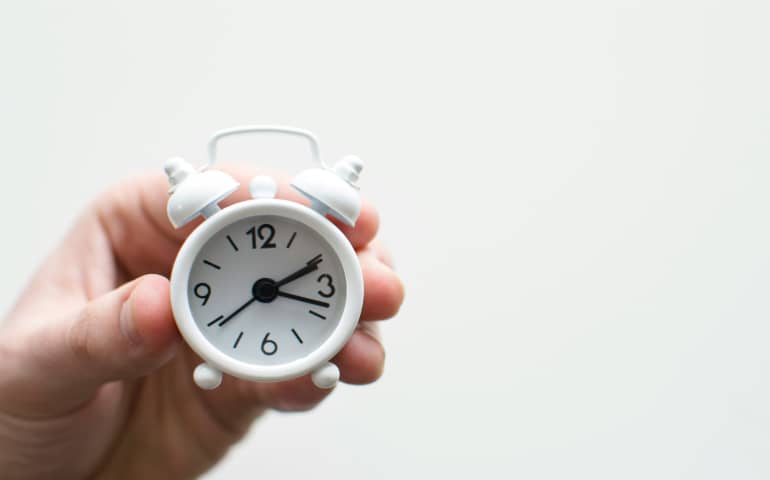 A white small clock showing time
