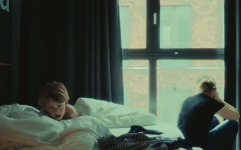 A baby on the bed of a hotel room