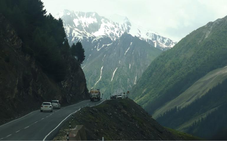 Cars travel along a winding mountain road with stunning snow-capped peaks in the background.
Image Credit - Akshay S/Pexels
