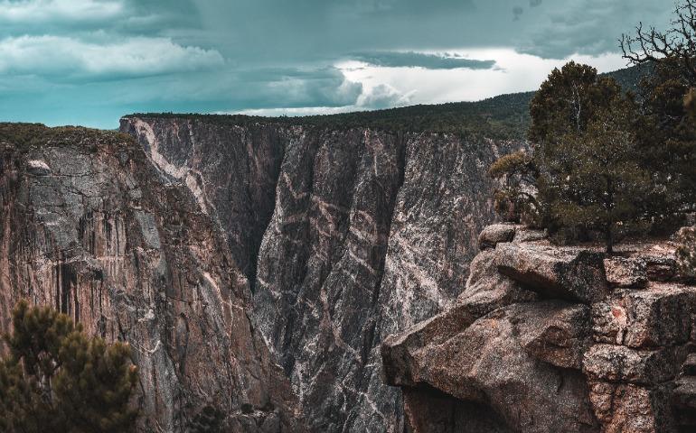Panoramic view of a dramatic rocky canyon landscape with greenery and a cloudy sky.
Image Credit: Alfo Medeiros/Pexels