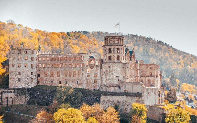 Heidelberg Castle, Germany, surrounded by vibrant autumn foliage on a sunny day.
Image Credit: Antonio Di Giacomo/Pexels 