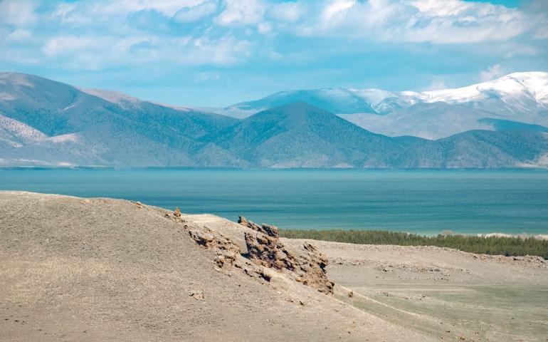 Tranquil view of a lake framed by hills and distant snowy mountains.
Image Credit: Arina Dmitrieva/Pexels