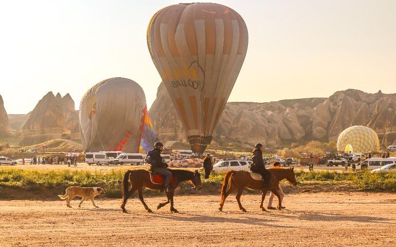 View of Cappadocia with hot air balloons and horse riders at sunrise.
Image Credit: azra irem Topcu/Pexels