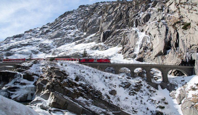 A vibrant red train traverses a scenic snowy viaduct in the Swiss Alps.
Image Credit: Ewa Schab/Pexels