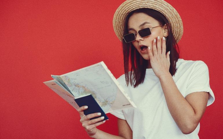 Young women with a passport and a map in hand, with a red background
Image Credit: Gustavo Fring/Pexels