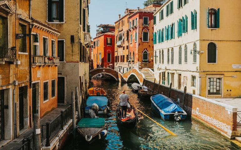 Charming canal scene in Venice with a gondola navigating under bridges
Image Credit: Helena Jankovičová Kováčová/Pexels