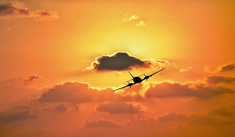A silhouette of an airplane flying against a vibrant sunset sky with clouds
Image Credit: Morteza Akhnia/Pexels