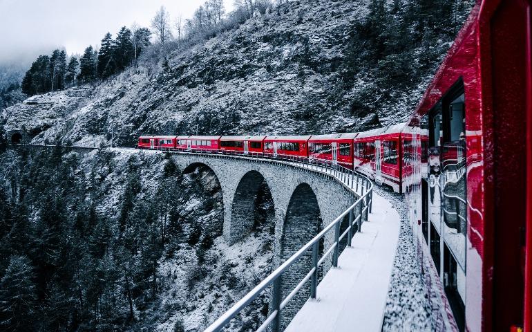 Red train on a snow-covered bridge in the Swiss Alps
Image Credit: Oskar Gross/Pexels