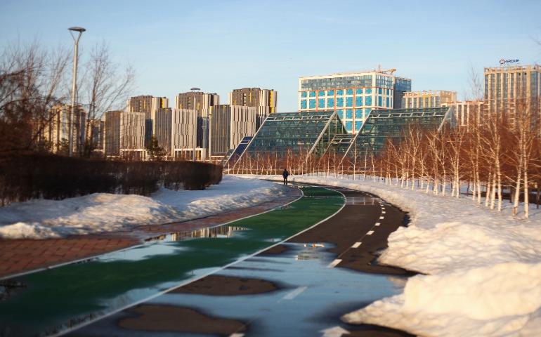 Astana in winter features modern buildings and a snowy urban park