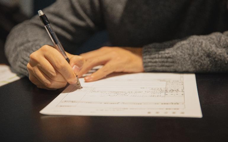 A man in a gray sweater signing a document at a desk
Image Credit: Ryutaro Tsukata/Pexels