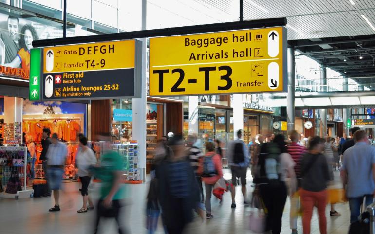 Crowded airport with motion blur and clear signage indicating baggage and arrival halls.
Image Credit: ClickerHappy/Pexels
