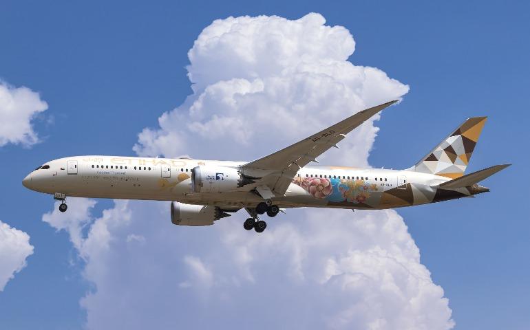 Etihad Airways Boeing 787 flying through a clear blue sky
