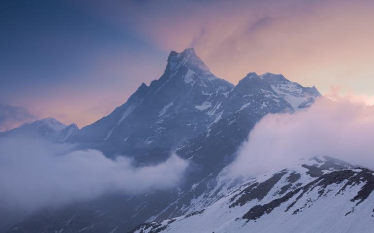 View of a snow-capped Himalayan mountain peak surrounded by clouds at sunset.
Image Credit: Sergey Guk/Pexels