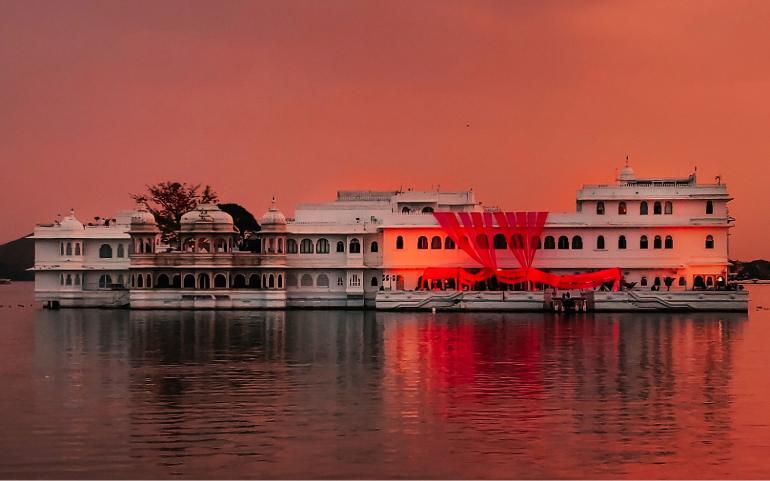 Lake Palace in Udaipur glows under a vibrant sunset, reflecting on serene waters.
Image Credit: Kunal Suthar/Pexels