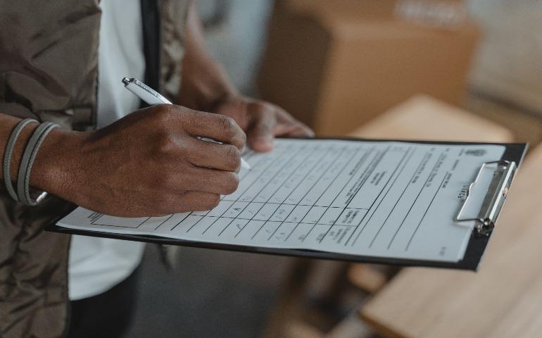 Close-up of person writing on form attached to clipboard.
Image Credit: Tima Miroshnichenko/Pexels