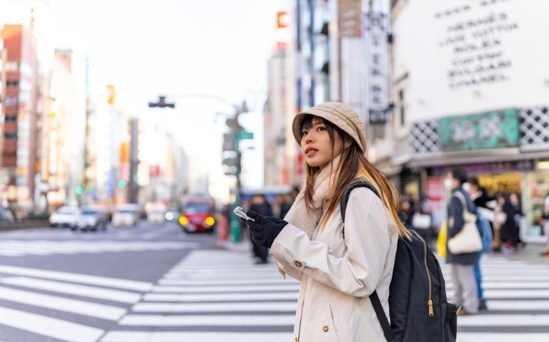 A tourist in Japan navigating the city with the help of a smartphone and esim
